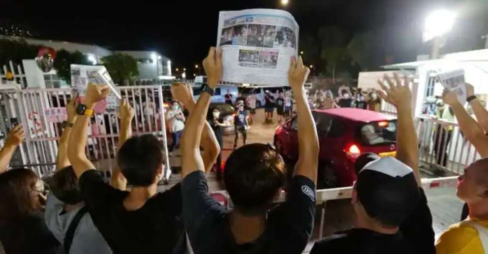 Apple Daily journalists hold freshly printed copies of the newspaper's last edition while acknowledging supporters gathered outside their office in Hong Kong on June 24, 2021. 