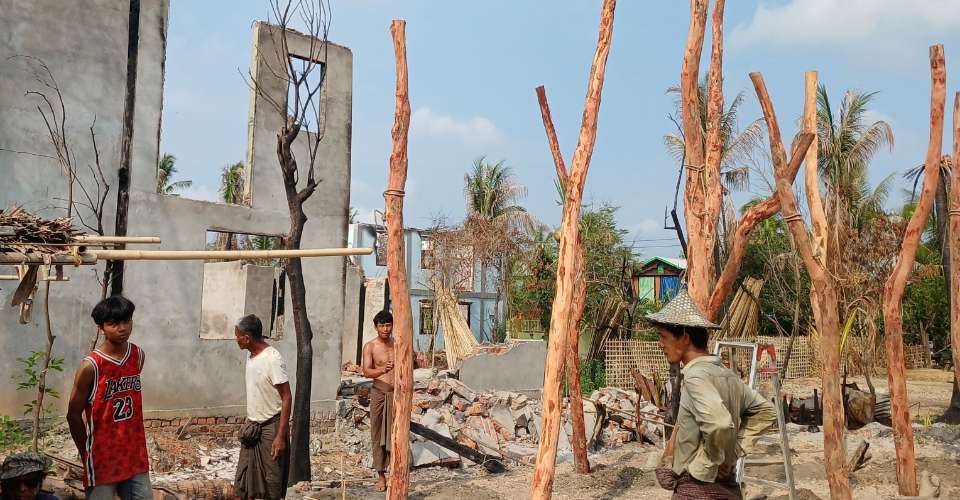People rebuild temporary homes near a destroyed building following fighting between Myanmar's military and the Arakan Army in a village in Minbya Township in western Rakhine State, on May 21.